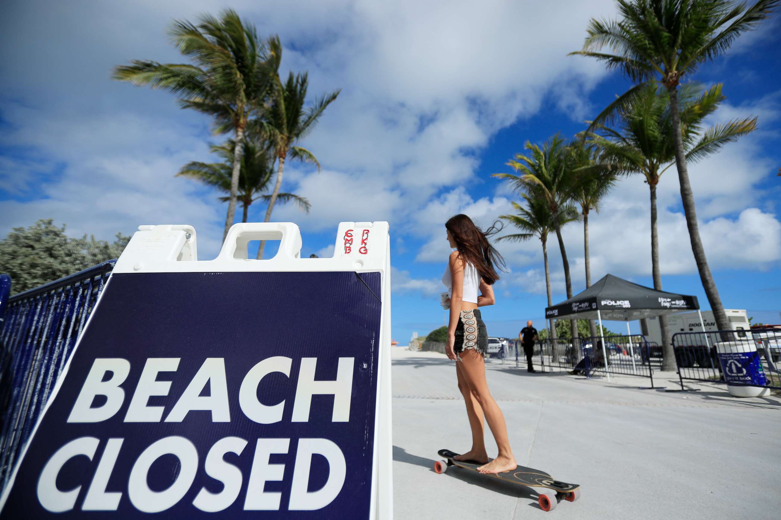 PHOTO: A skateboarder passes a "Beach Closed" sign on the boardwalk on March 22, 2020 in Miami Beach, Florida. The city of Miami Beach has closed all parks and beaches due to COVID-19, however the boardwalk is open for people to exercise.