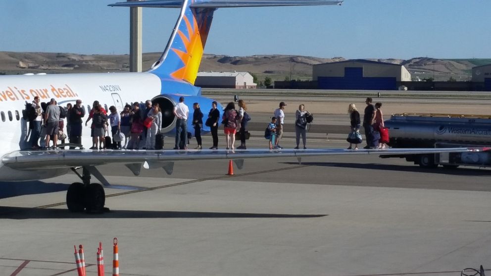 Passengers from Allegiant Air flight 330 stand on the wing of the plane in Boise, Idaho, following an evacuation over a fuel spill on June 12, 2015. 