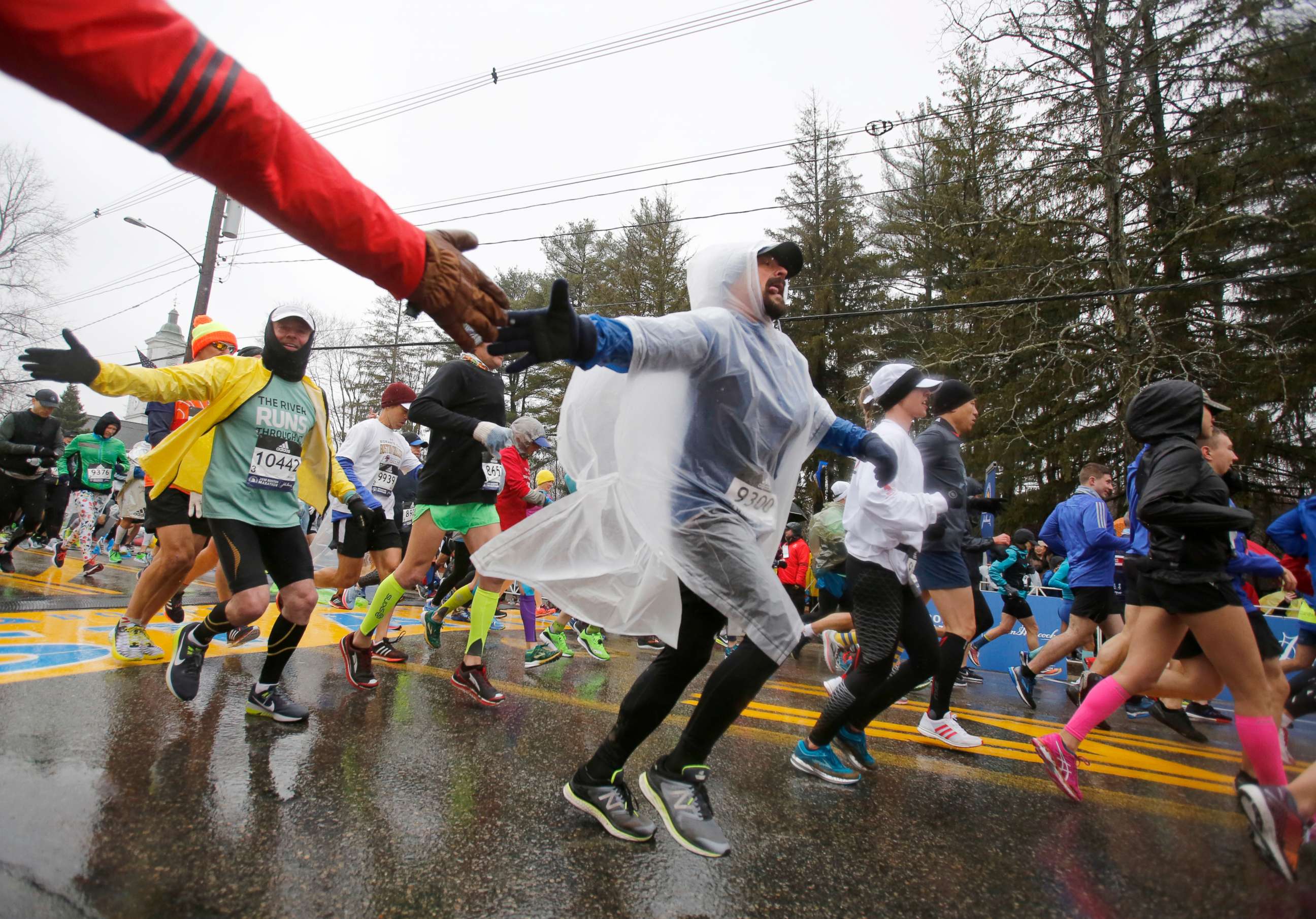 PHOTO: Wearing a plastic poncho, Manuel Gonzalez (9300), from Illinois, reaches out for a high-five just after crossing the starting line during the 122nd running of the Boston Marathon, April 16, 2018. 