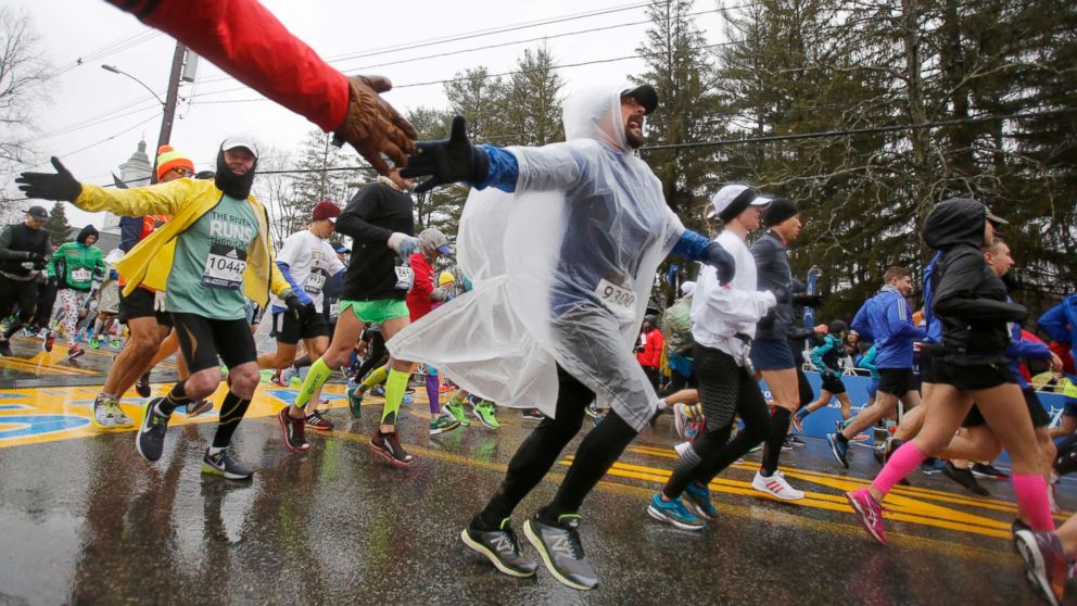 PHOTO: Wearing a plastic poncho, Manuel Gonzalez (9300), from Illinois, reaches out for a high-five just after crossing the starting line during the 122nd running of the Boston Marathon, April 16, 2018. 