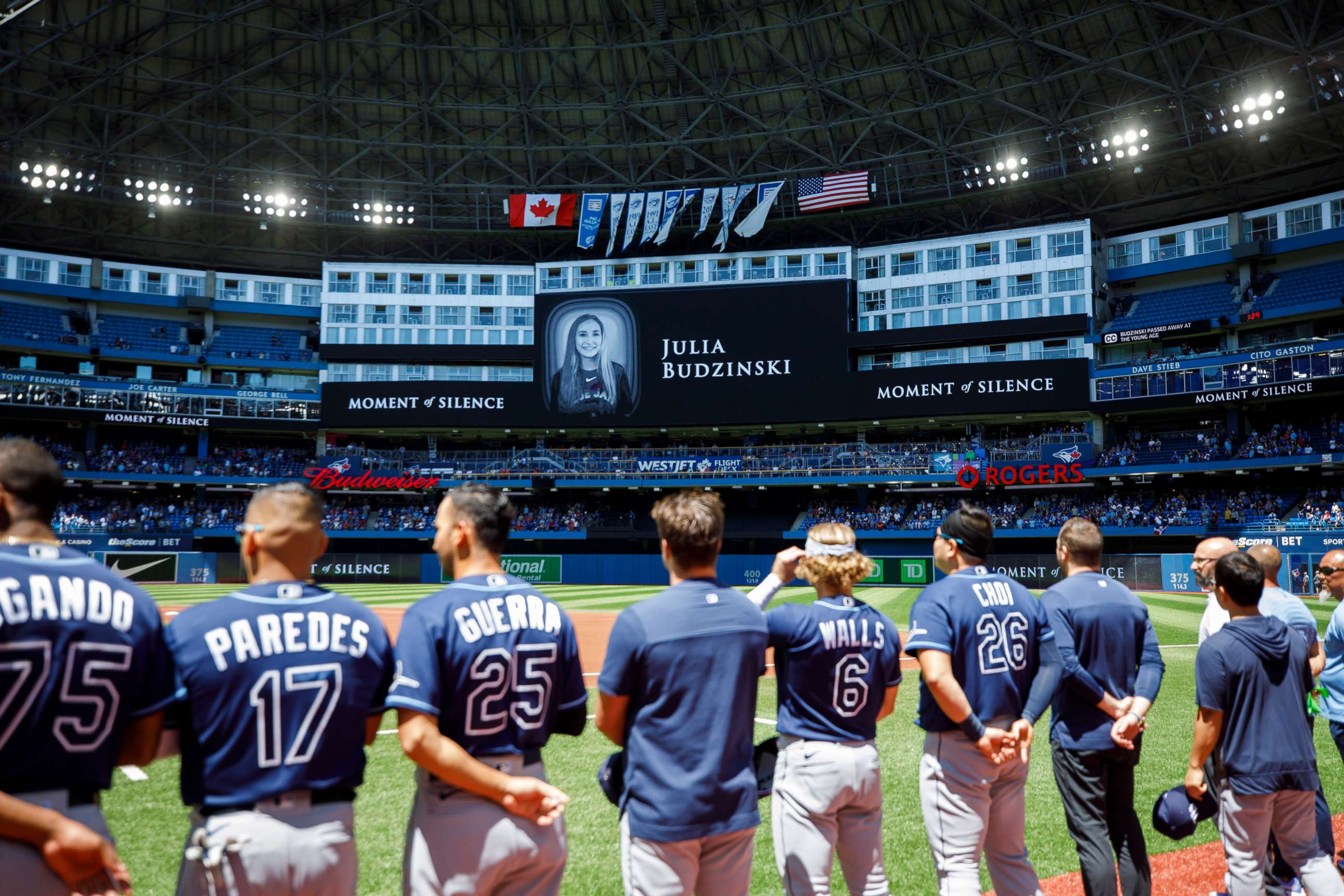 PHOTO: Tampa Bay Rays players and staff stand for a moment of silence on the death of Julia Budzinski, the eldest daughter of first base coach Mark Budzinski, ahead of a game against the Tampa Bay Rays at Rogers Centre, July 3, 2022, in Toronto, Canada.