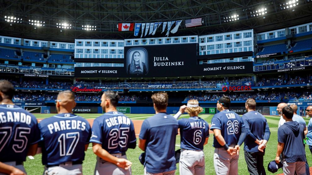PHOTO: Tampa Bay Rays players and staff stand for a moment of silence on the death of Julia Budzinski, the eldest daughter of first base coach Mark Budzinski, ahead of a game against the Tampa Bay Rays at Rogers Centre, July 3, 2022, in Toronto, Canada.