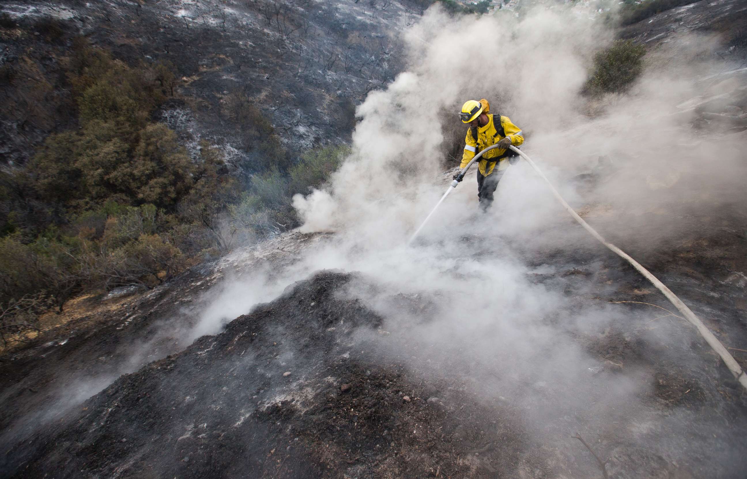PHOTO: LA County firefighter Kevin Sleight extinguishes hot spots while battling the La Tuna Canyon fire. Firefighters were assisted by cooler temperatures and brief showers in their battle against the 5,900-acre brush fire north of downtown Los Angeles. 