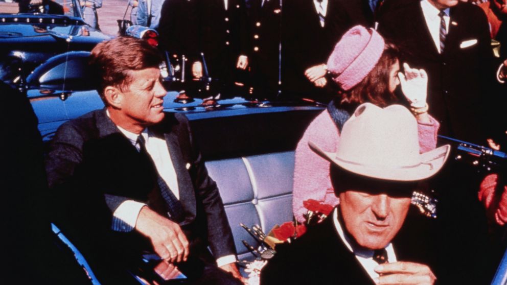 Texas Governor John Connally adjusts his tie (foreground) as President and Mrs. Kennedy, in a pink outfit, settled in rear seats, prepared for motorcade into city from airport, Nov. 22, 1963 in Dallas. 
