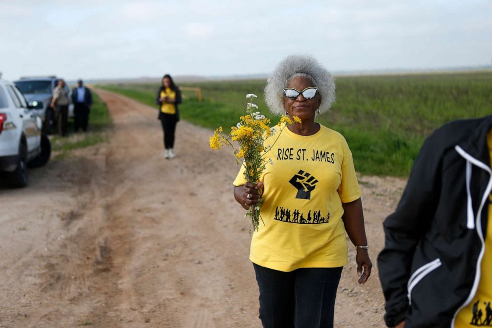 PHOTO: Gail LeBoeuf, a member of RISE St. James, carries flowers as they seek access to a burial site on property owned by Formosa in St. James Parish, La., March 11, 2020. 