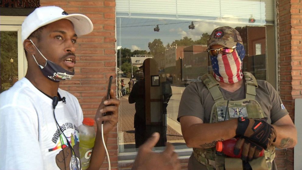 PHOTO: Aaron Clarke talks to a militia member in Harrison, Arkansas, during a demonstration, part of which he live streamed on Facebook.
