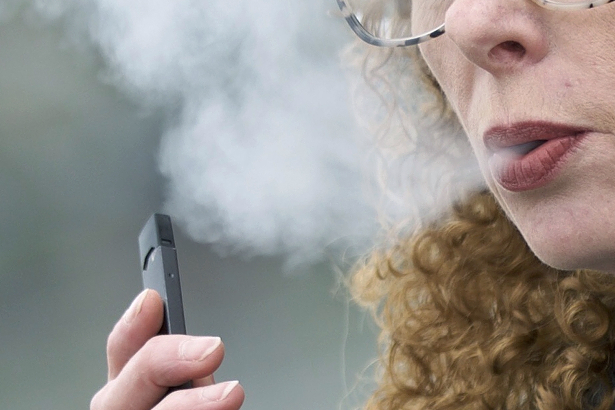 PHOTO: In this April 16, 2019 file photo, a woman exhales while vaping from a Juul pen e-cigarette. On Wednesday, Feb. 12, 2020, Massachusetts sued Juul Labs Inc, accusing the company of deliberating targeting young people through its marketing campaigns.