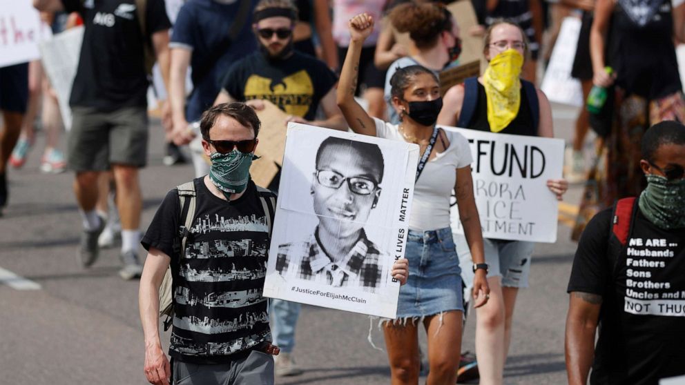 PHOTO: Demonstrators carry placards as they walk down Sable Boulevard during a rally and march over the death of 23-year-old Elijah McClain, June 27, 2020, in Aurora, Colo. 