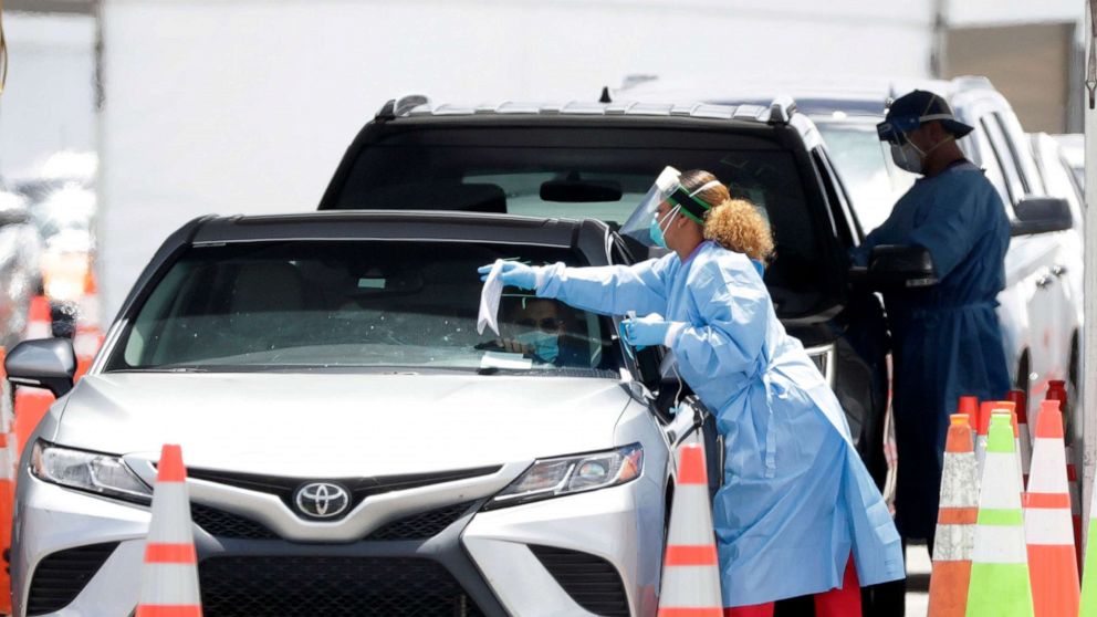 PHOTO: Healthcare workers prepare to test drivers at a drive-through coronavirus testing site outside of Hard Rock Stadium, June 26, 2020, in Miami Gardens, Fla.