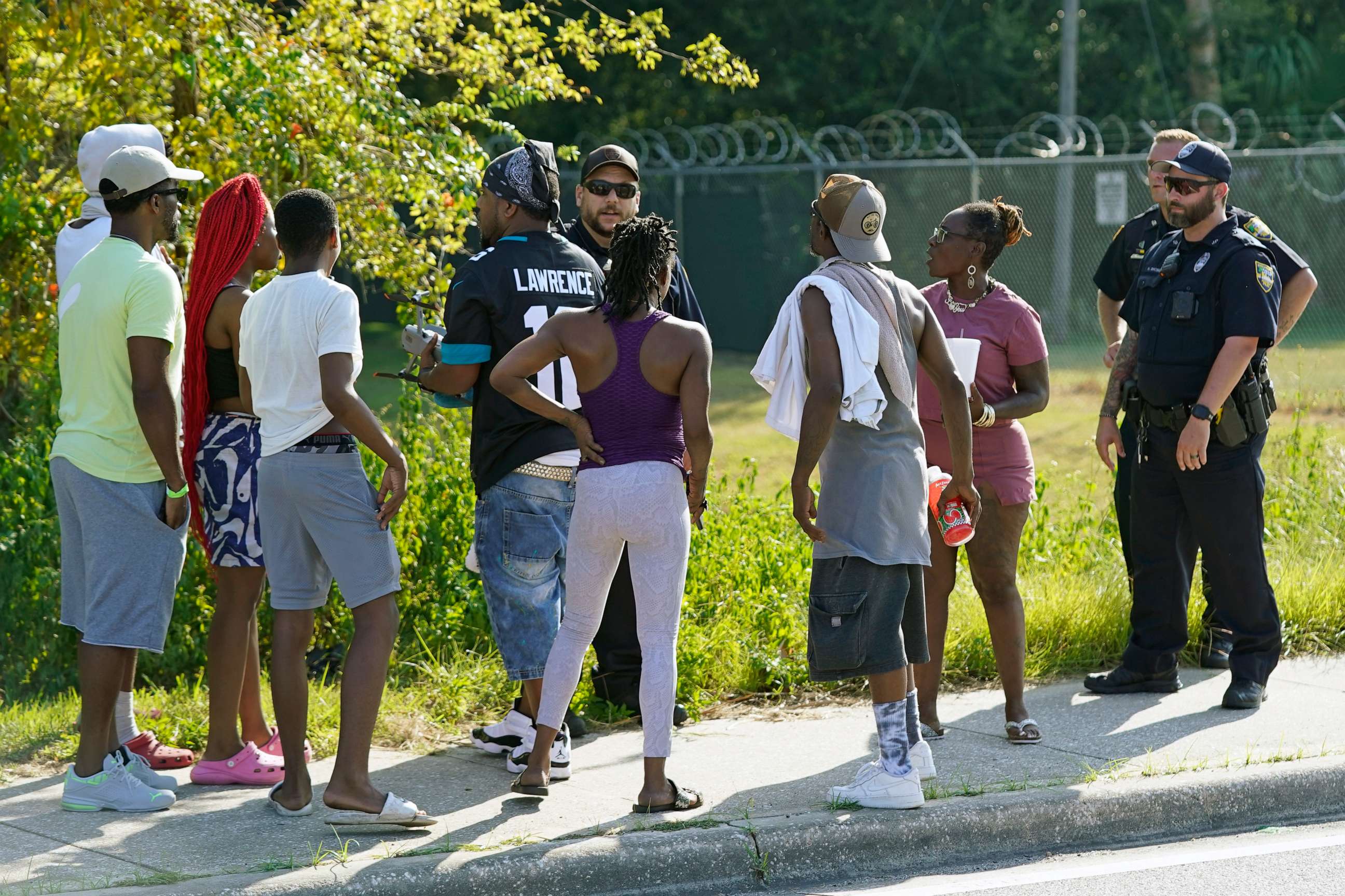 PHOTO: Residents talk with Jacksonville police officers near the scene of a mass shooting at a Dollar General store, Saturday, Aug. 26, 2023, in Jacksonville, Fla. (AP Photo/John Raoux)