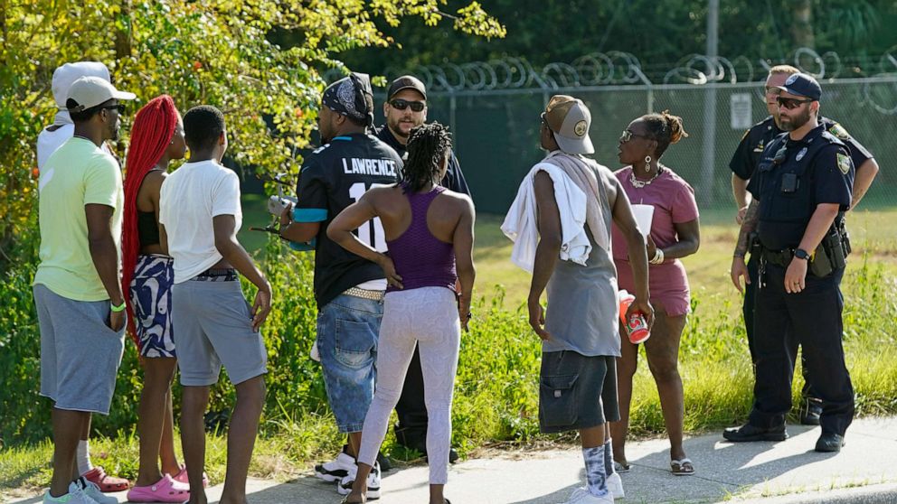 PHOTO: Residents talk with Jacksonville police officers near the scene of a mass shooting at a Dollar General store, Saturday, Aug. 26, 2023, in Jacksonville, Fla. (AP Photo/John Raoux)