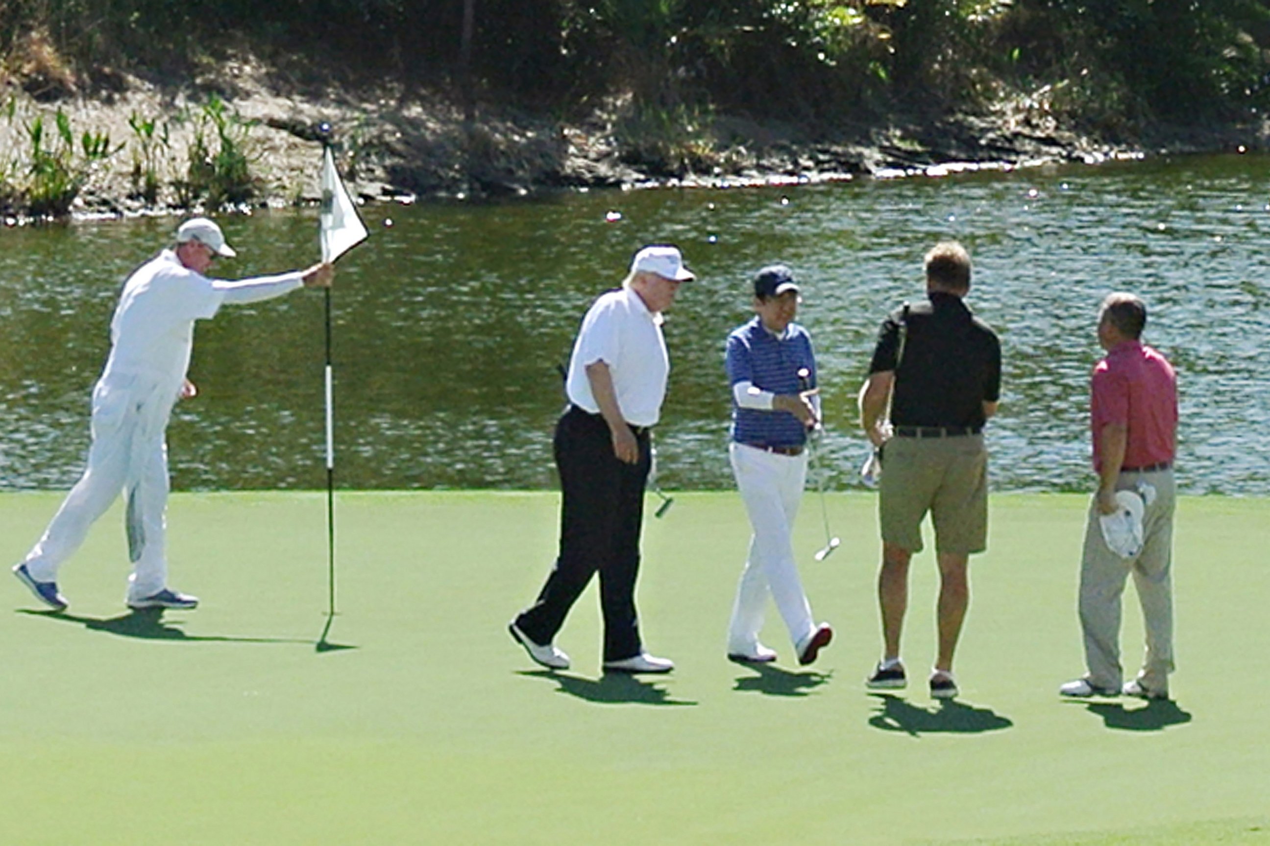 PHOTO: President Donald Trump, wearing black pants, and Japan's Prime Minister Shinzo Abe, third from right, enjoy playing golf, Feb. 11, 2017, in Florida.