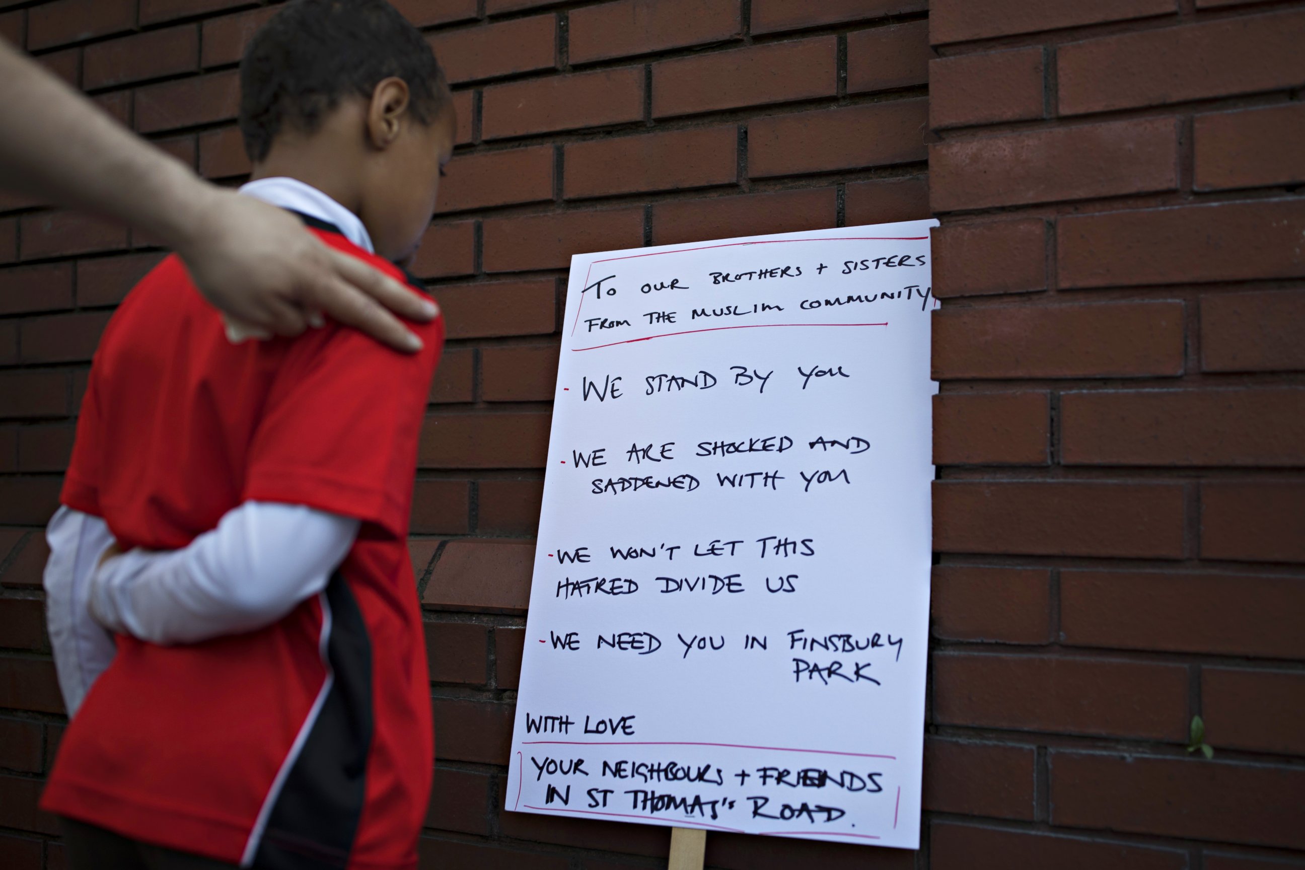 PHOTO: A boy reads a sign outside Finsbury Park Mosque on June 19, 2017 in London. Worshippers were struck by a hired van as they were leaving the mosque following Ramadan prayers