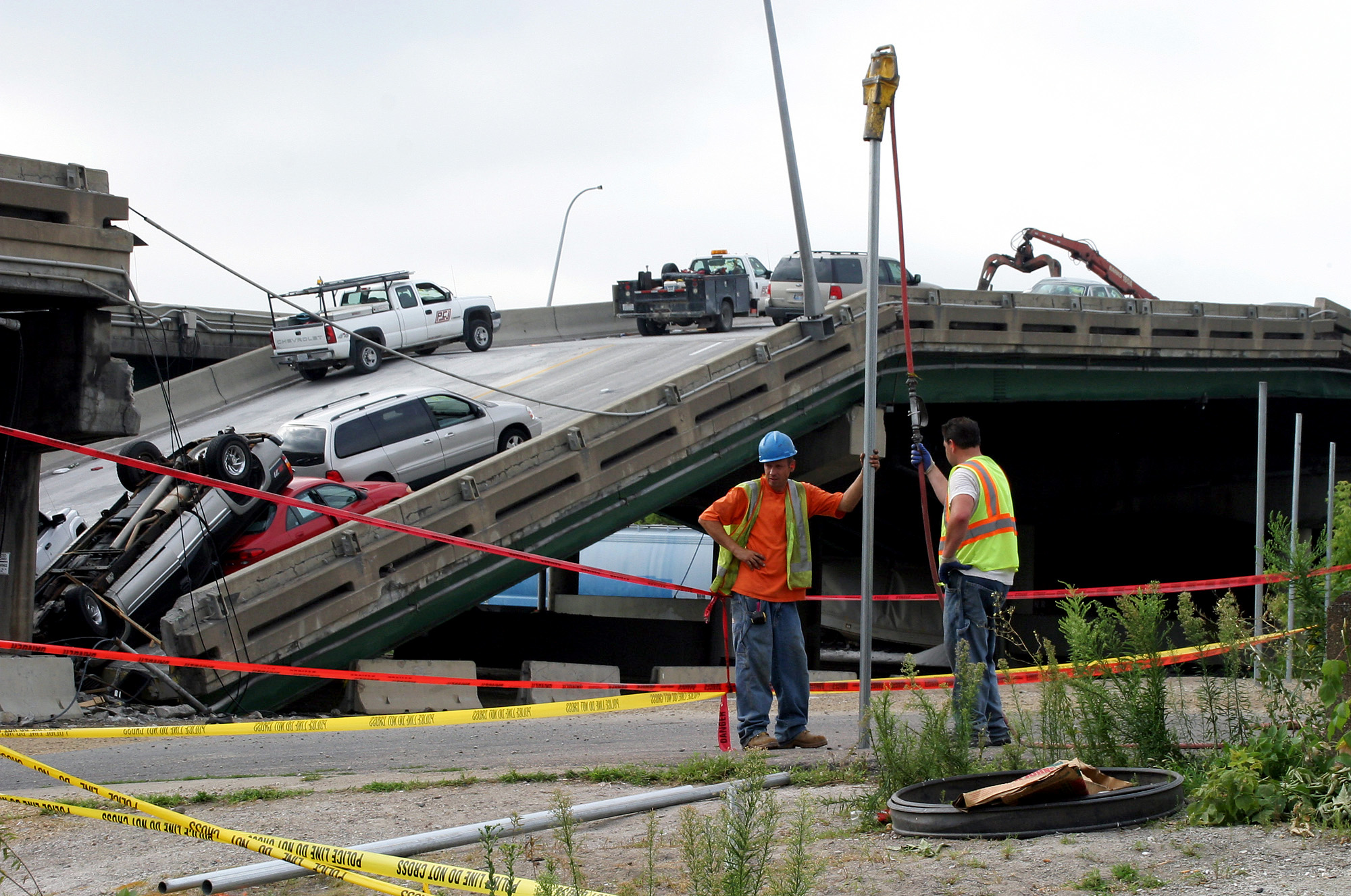 PHOTO: Workers build a metal fence, Aug. 7, 2007, along police tape where the I-35W bridge collapsed over the Mississippi River in Minneapolis, Minnesota. 