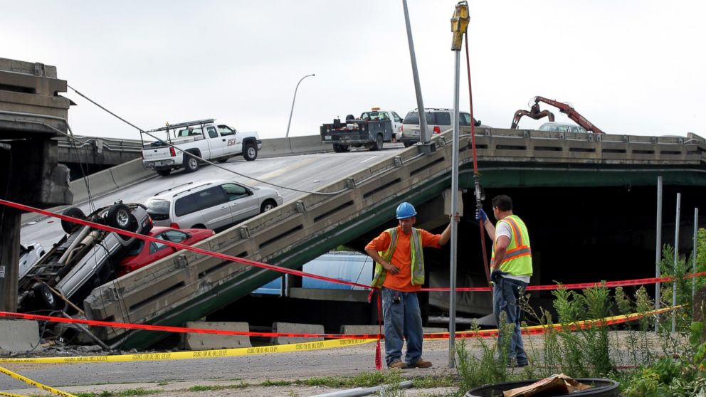 PHOTO: Workers build a metal fence, Aug. 7, 2007, along police tape where the I-35W bridge collapsed over the Mississippi River in Minneapolis, Minnesota.