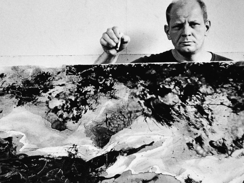 PHOTO: American abstract expressionist painter Jackson Pollock holds a cigarette with one of his paintings in his studio at The Springs, East Hampton, N.Y., Aug. 23, 1953.