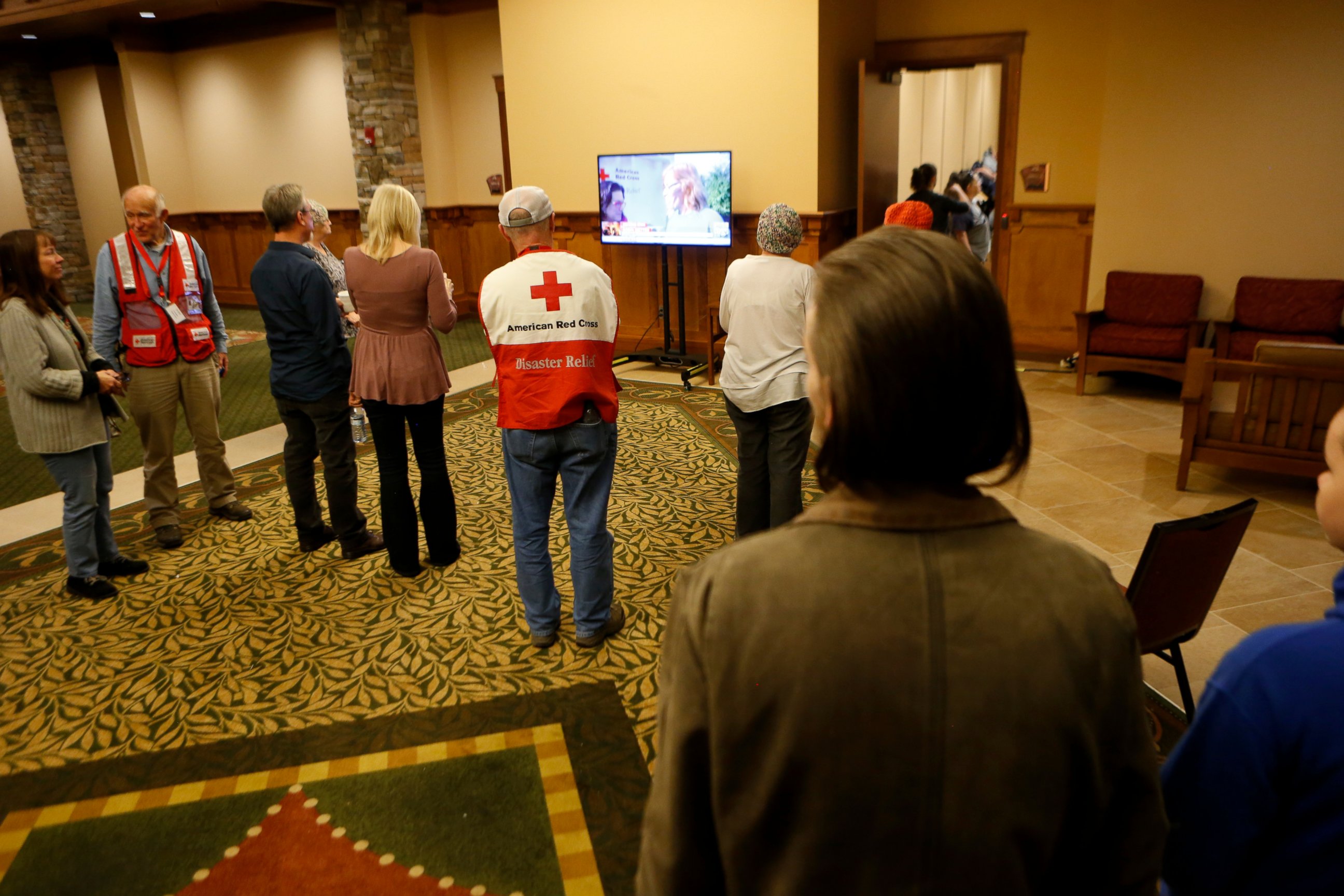 PHOTO: Volunteers and evacuees watch a news segment about the nearby fire in Gatlinburg, Tennessee at a shelter, on Nov. 29, 2016, in Pigeon Forge, Tennessee. 