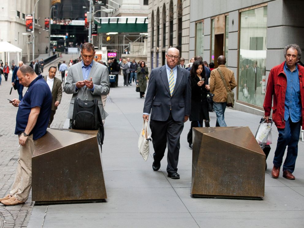 PHOTO: Commuters walk to work down Wall Street past artistic security barricades near the NYSE, April 11, 2013 in New York.