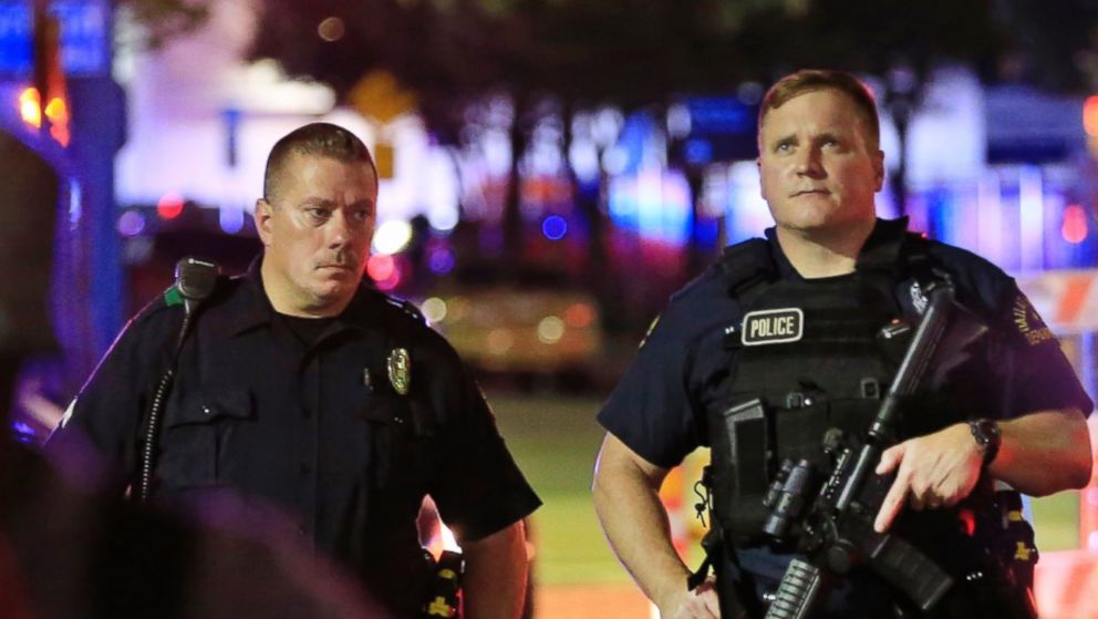 Dallas police and residents stand near the scene where Dallas police officers were shot and killed on July 7, 2016 in Dallas, Texas.