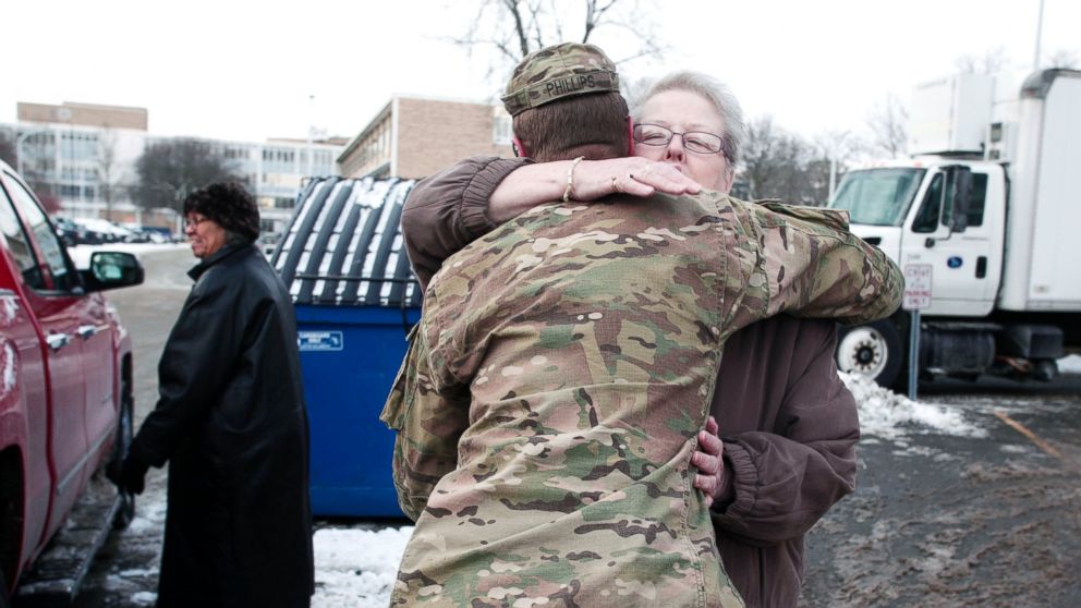 PHOTO: Michigan National Guard Staff Sergeant William Phillips gets a hug from a Flint resident after helping her carry bottled water to her car at a Flint Fire Station on Jan. 13, 2016 in Flint, Mich. 