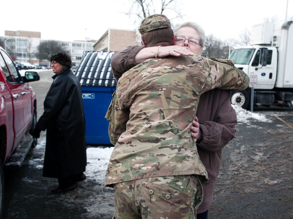 PHOTO: Michigan National Guard Staff Sergeant William Phillips gets a hug from a Flint resident after helping her carry bottled water to her car at a Flint Fire Station on Jan. 13, 2016 in Flint, Mich. 