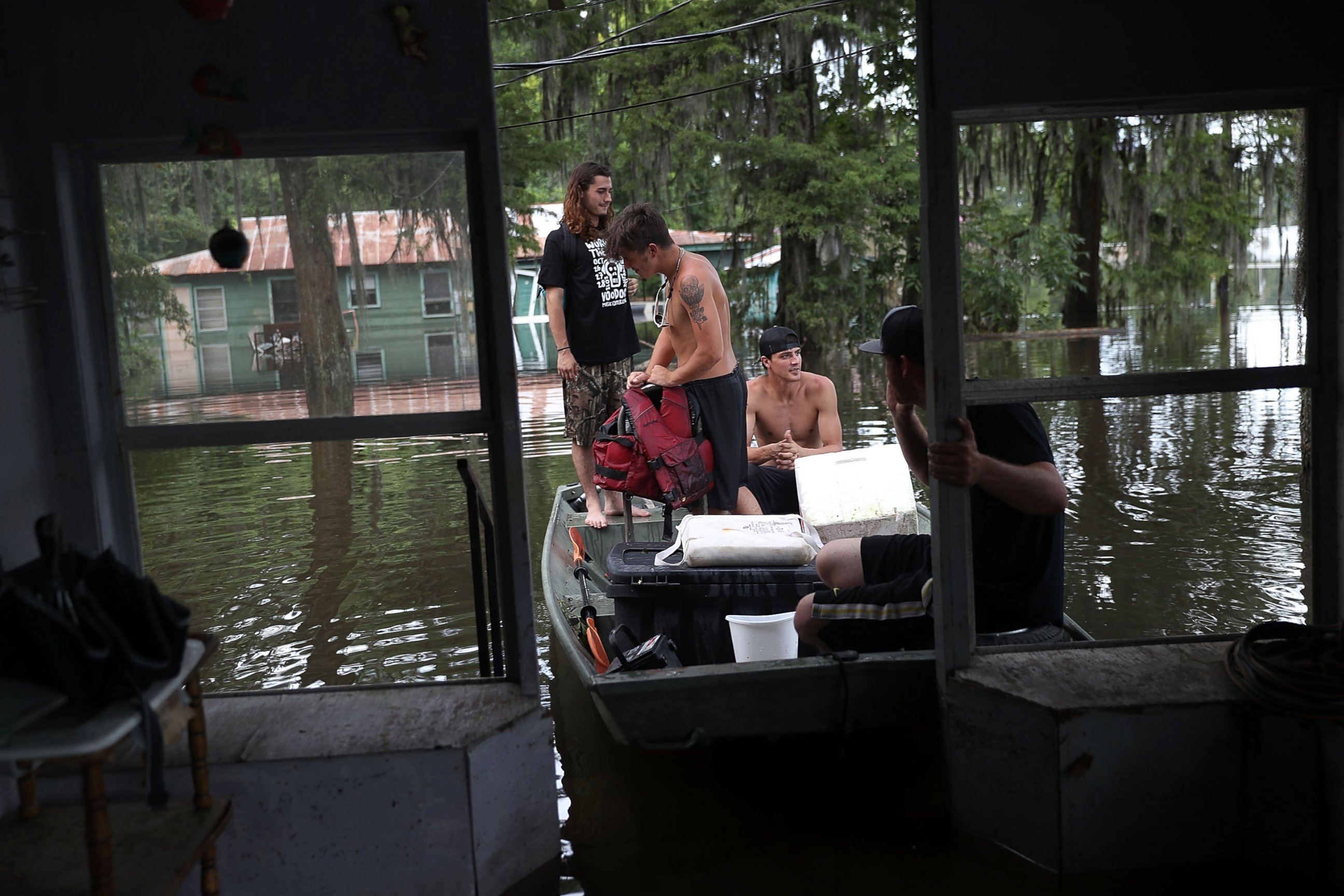 PHOTO: Bryce Richard, Nick Rome and Blake Waguespack (L-R) wait in the boat for a friend to check out her flooded house, on Aug. 18, 2016, in Sorrento, Louisiana.  