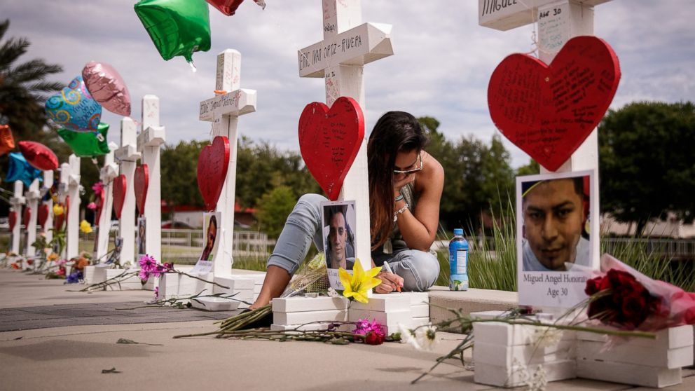 A woman writes a note on a cross for Eric Ivan Ortiz-Rivera at a memorial with wooden crosses for each of the 49 victims of the Pulse Nightclub, next to the Orlando Regional Medical Center, June 17, 2016 in Orlando, Fla. 