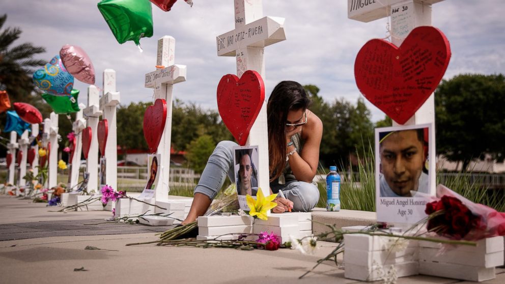 A woman writes a note on a cross for Eric Ivan Ortiz-Rivera at a memorial with wooden crosses for each of the 49 victims of the Pulse Nightclub, next to the Orlando Regional Medical Center, June 17, 2016 in Orlando, Fla.