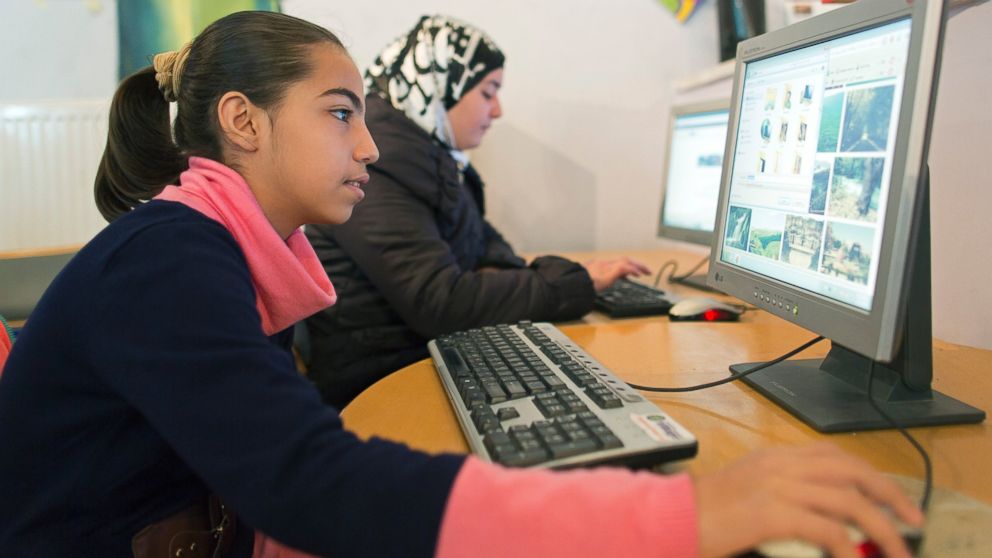 PHOTO: Two girls surf the internet in the child and family protection zone for Syrian refugees in Jordan. 