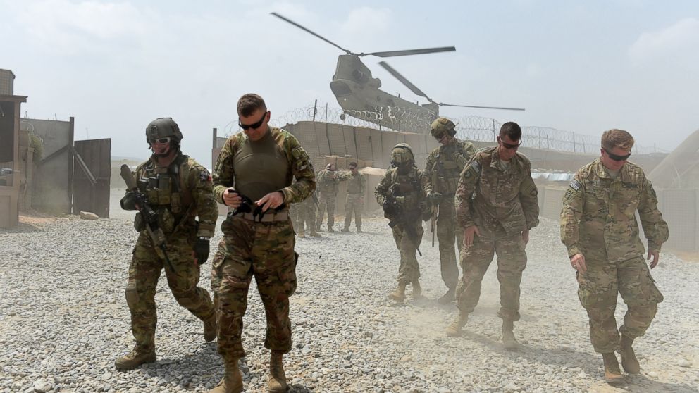 In this photograph taken on August 13, 2015, US army soldiers walk as a NATO helicopter flies overhead at coalition force Forward Operating Base (FOB) Connelly in the Khogyani district in the eastern province of Nangarhar. 