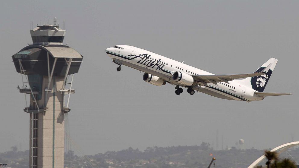 An Alaska Airlines jet passes the air traffic control tower at Los Angles International Airport (LAX) during take-off.