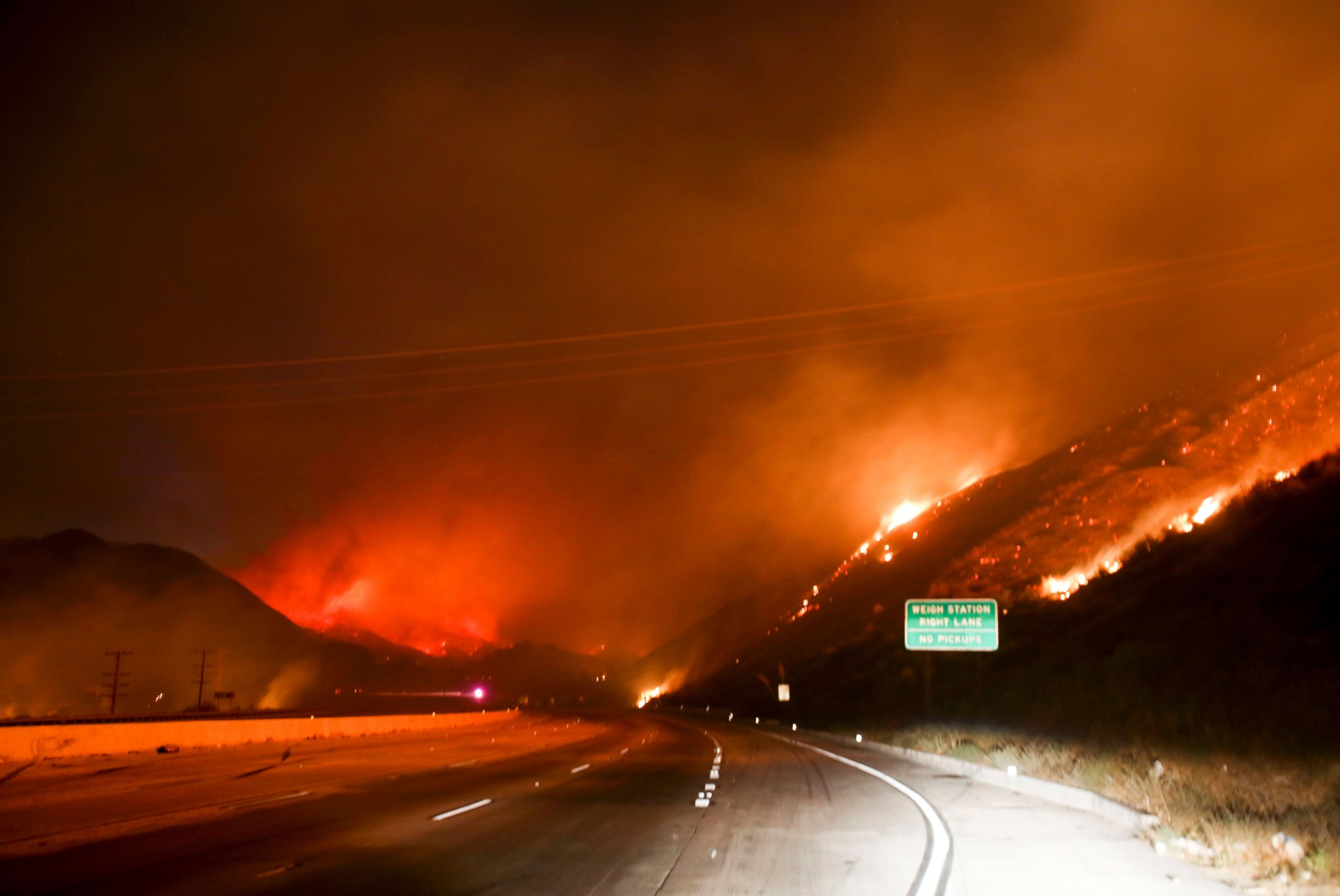 PHOTO: Flames burn next to the Interstate 15 as the Blue Cut wildfire rages near Cajon Pass, north of San Bernardino, California, Aug. 16, 2016. 