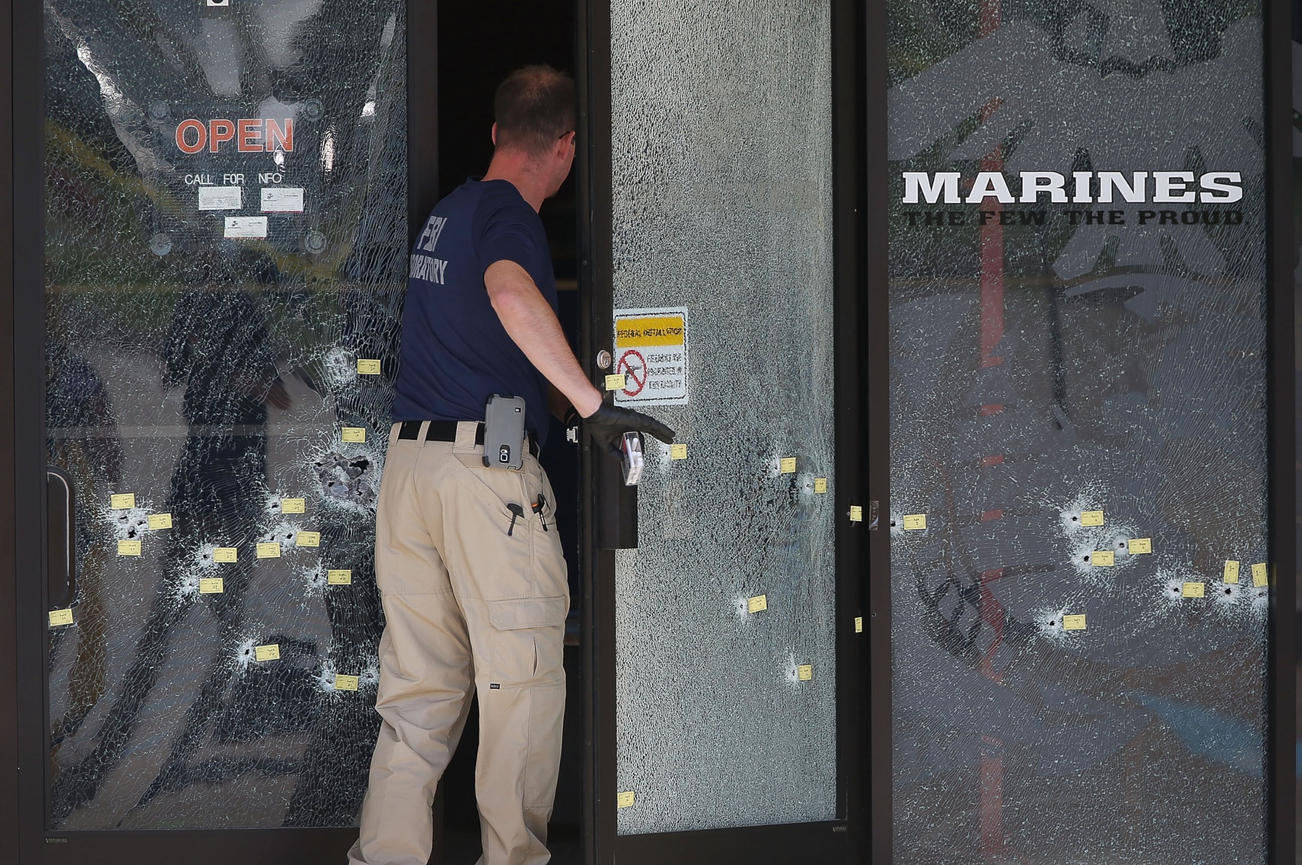 PHOTO: A member of the F.B.I. Evidence Response Team walks through a bullet riddled door as he investigates the shooting at the Armed Forces Career Center/National Guard Recruitment Office, July 17, 2015 in Chattanooga, Tennessee.