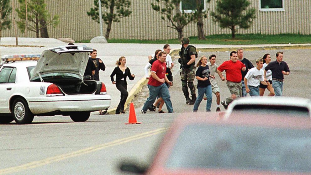 Students from Columbine High School run under cover from police in Littleton, Colo., April 20, 1999.
