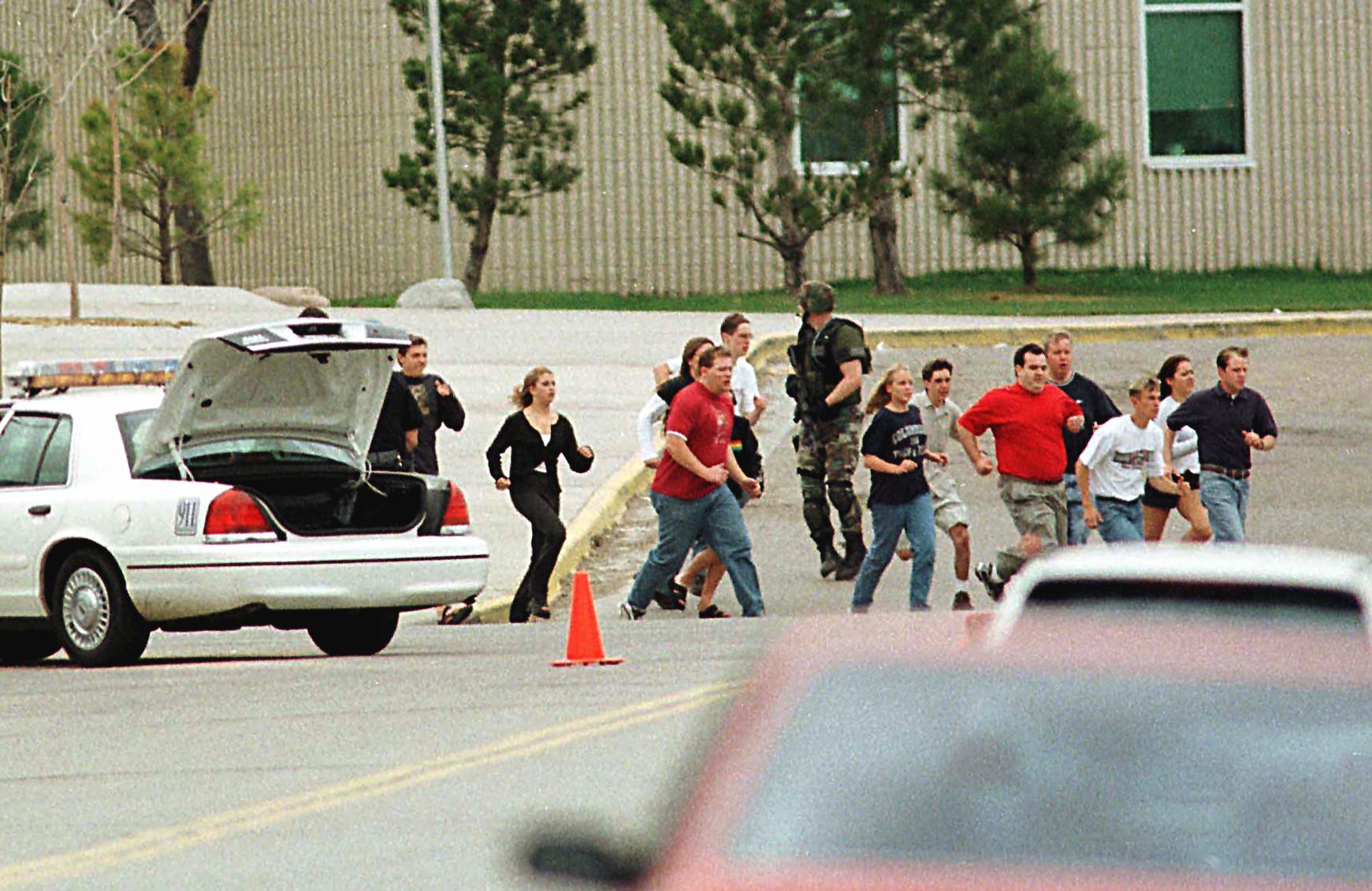 PHOTO: Students from Columbine High School run under cover from police in Littleton, Colo.