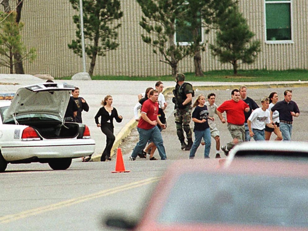 PHOTO: Students from Columbine High School run under cover from police in Littleton, Colo.