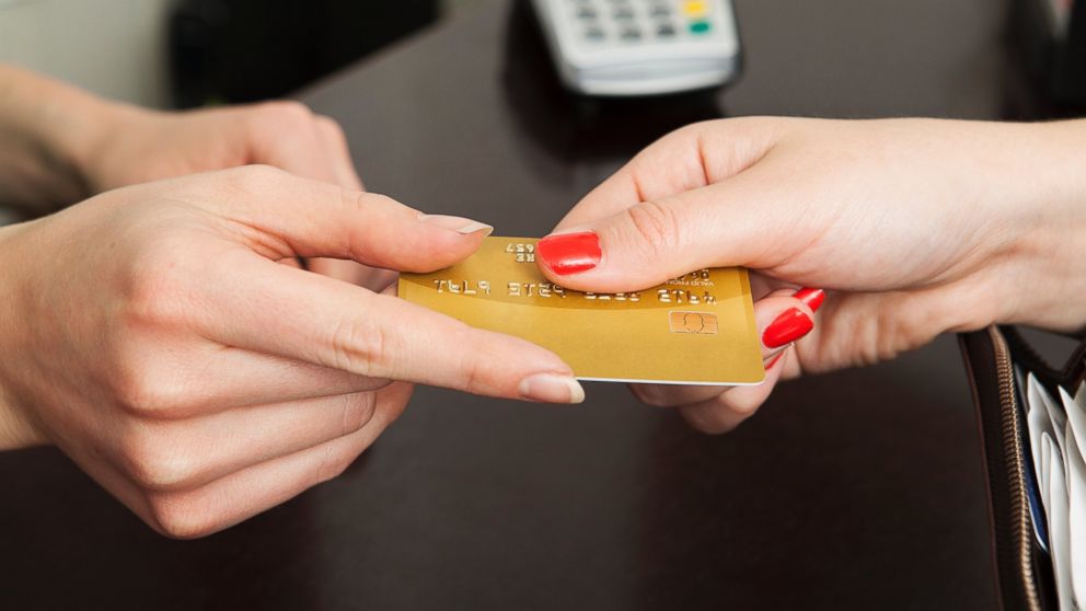 A woman hands over a credit card for payment.