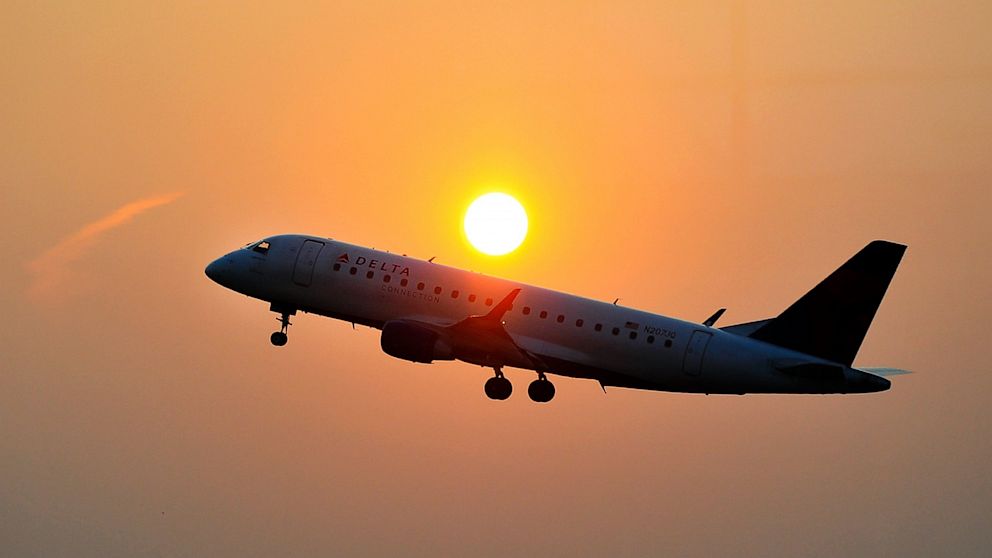 A Delta airline's aircraft takes off from the airport as the sun rises.