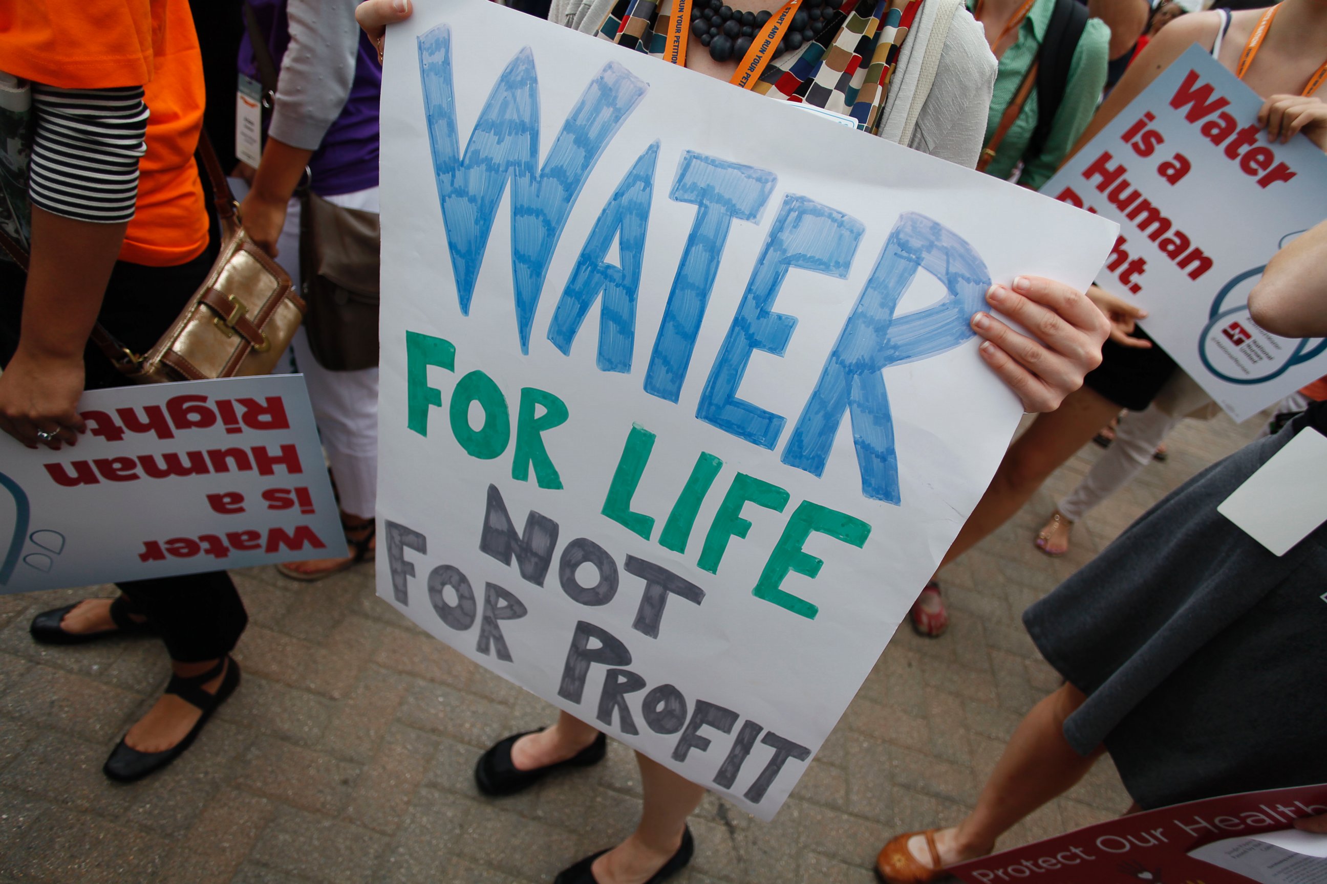 PHOTO: Demonstrators hold signs as they protest against the Detroit Water and Sewer Department July 18, 2014 in Detroit, Mich.  
