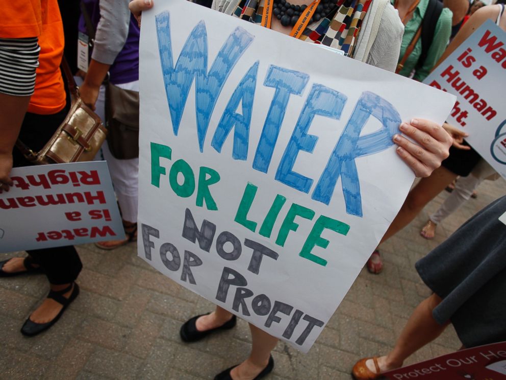 PHOTO: Demonstrators hold signs as they protest against the Detroit Water and Sewer Department July 18, 2014 in Detroit, Mich.