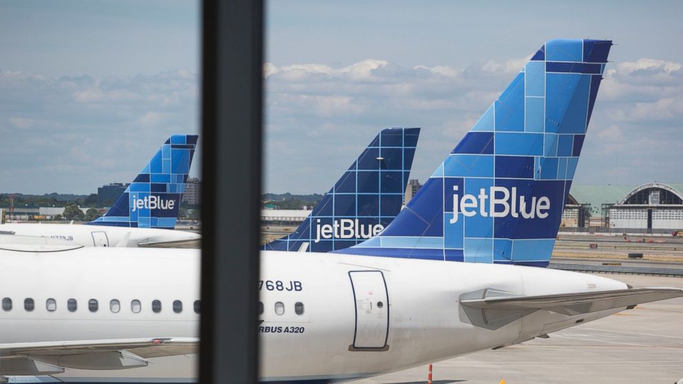 In this file photo, JetBlue Airways Corp. planes sit on the tarmac as a passenger waits in Terminal 5 at John F. Kennedy International Airport airport in New York, Aug. 7, 2015. 