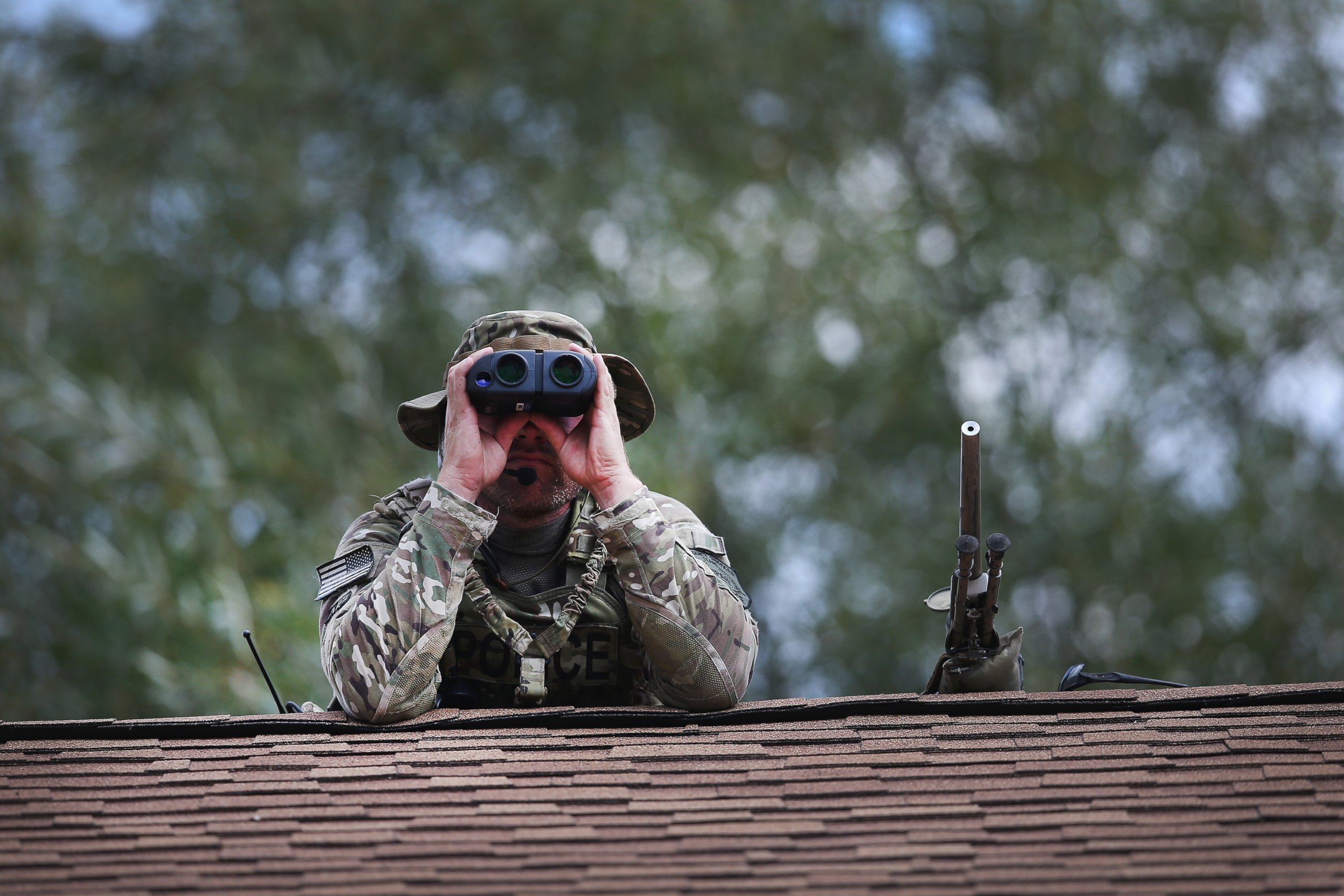 PHOTO:A police sniper keeps watch from the roof of a home while other police search nearby for suspects involved in the shooting of an officer, Sept. 1, 2015, in Fox Lake, Ill.  
