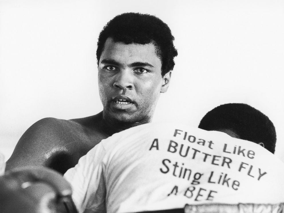 PHOTO: Muhammad Ali seen here in this 1970 file photo. The man in front of him is wearing a t-shirt printed with Ali's motto 'Float like a butterfly, sting like a bee'.