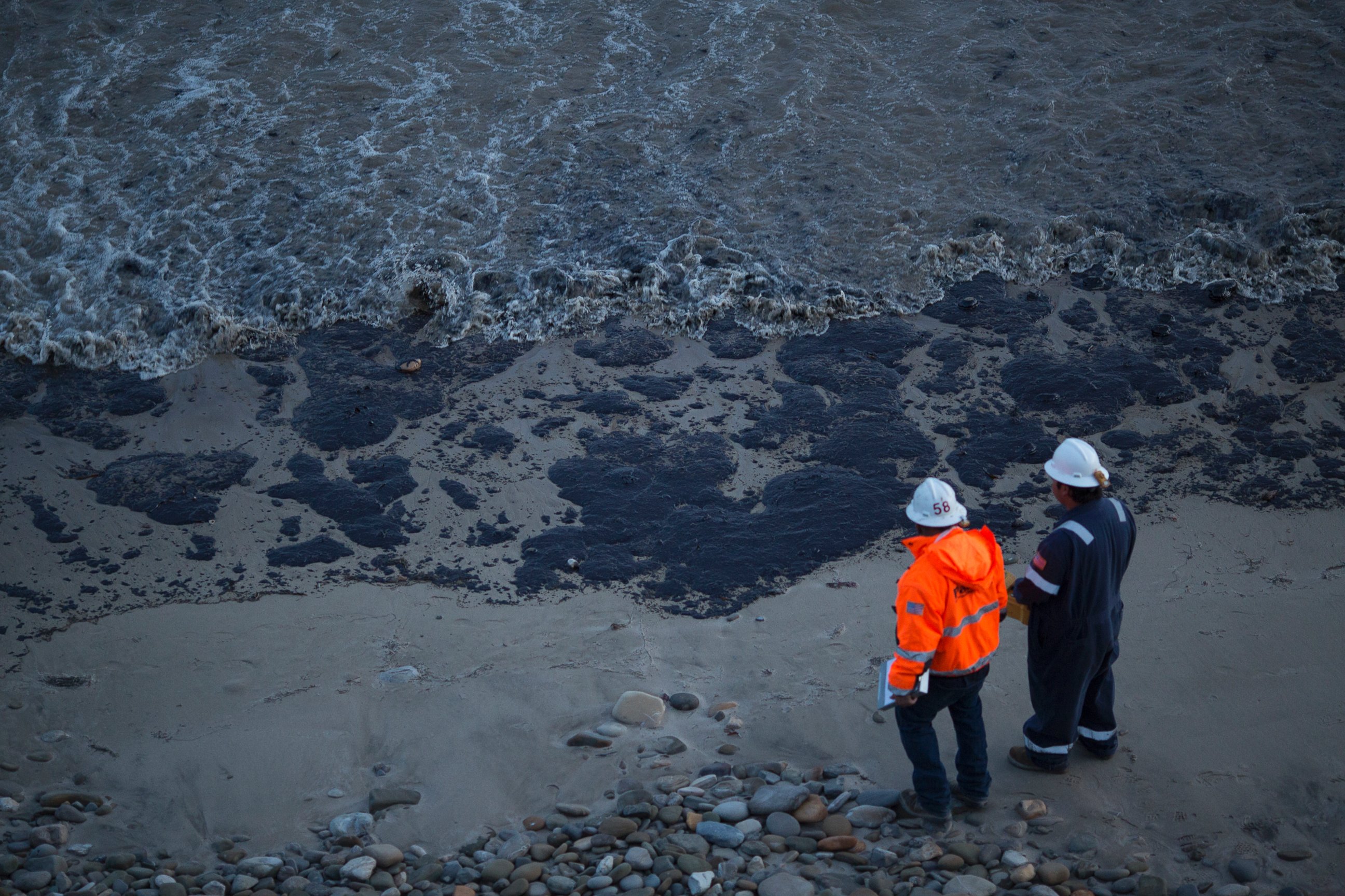 PHOTO: Officials walk along an the oil-covered beach on May 19, 2015 north of Goleta, Calif.
