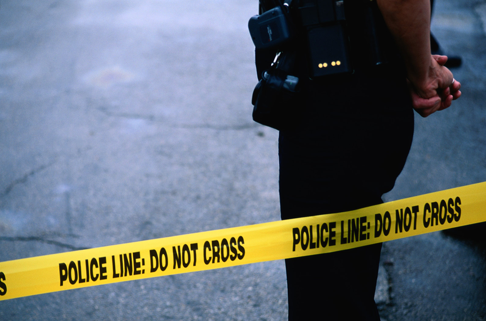 PHOTO: A police officer stands behind tape. 