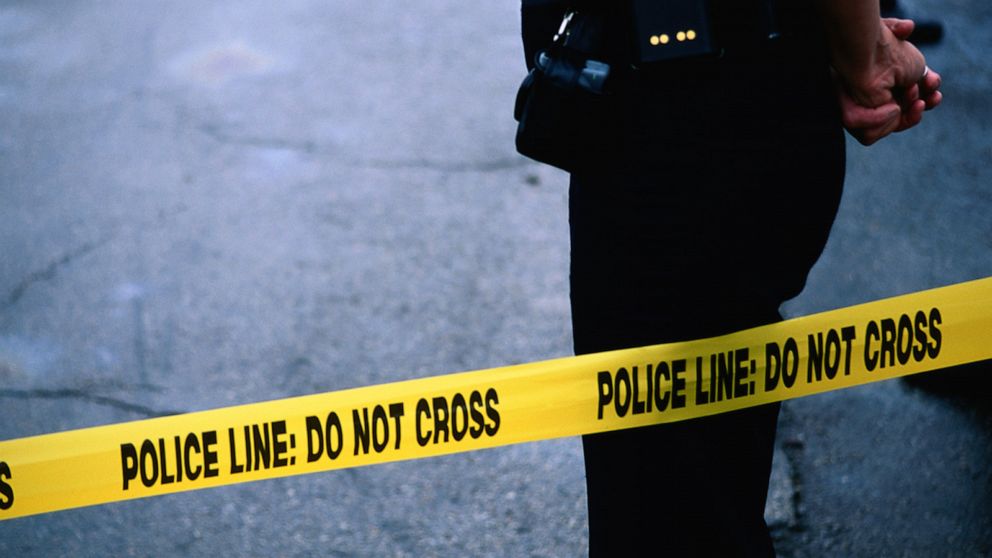 PHOTO: A police officer stands behind tape. 