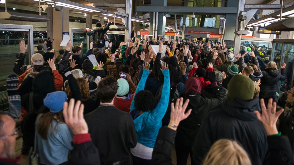PHOTO: Black Lives Matter protesters hold their hands in the air and chant, "Hands up, don't shoot," at the Minneapolis-St. Paul International airport Lightrail stop, Dec. 23, 2015 in Minneapolis.