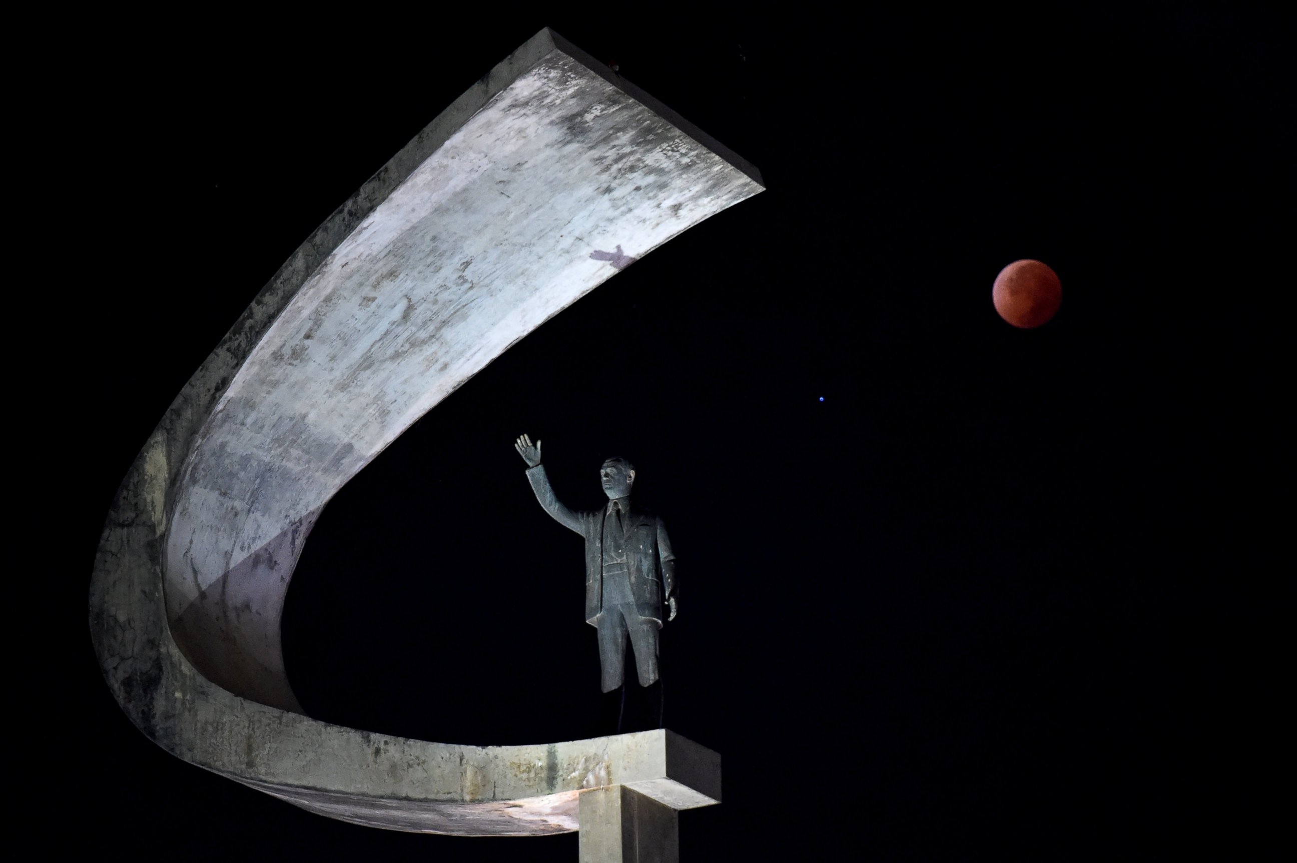 PHOTO: The moon during a total lunar eclipse over the Juscelino Kubitschek Memorial in Brasilia, Brazil.