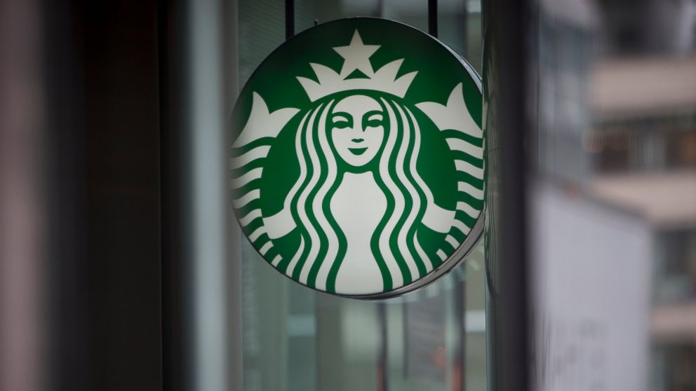 Pedestrians pass in front of a Starbucks Corp. location in New York, U.S., on Tuesday, April 23, 2013.