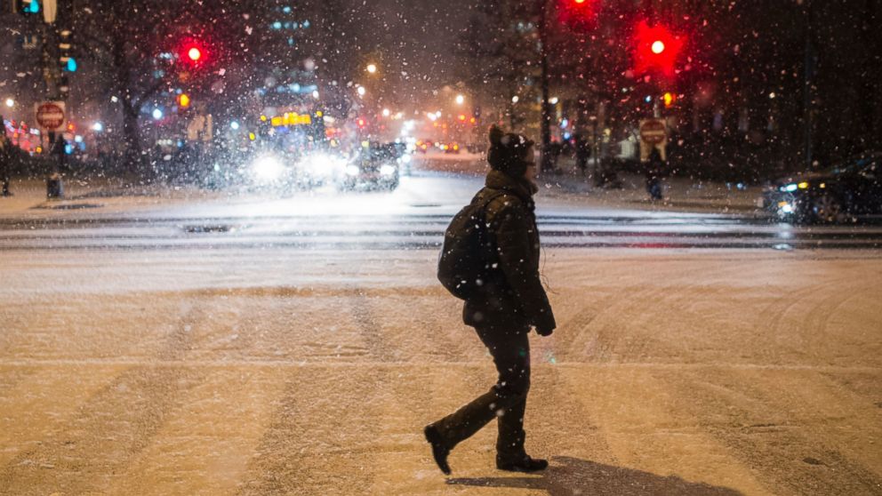 A woman crosses the street as it snows in Washington,  Jan.20, 2016. 
